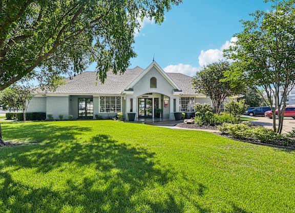 the front of a house with a lawn and trees