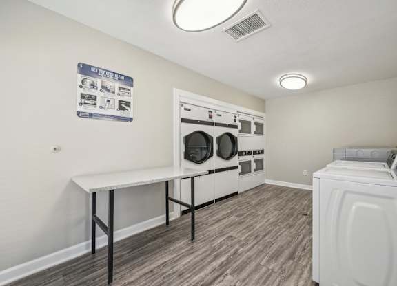 a washer and dryer in a laundry room with white walls and wood floors