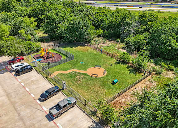 a park with a playground and cars parked in a parking lot