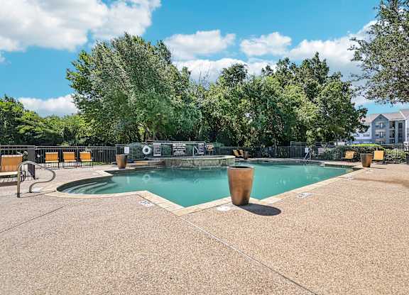 a swimming pool with trees and a building in the background