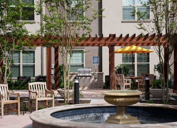 a fountain in a courtyard with tables and chairs