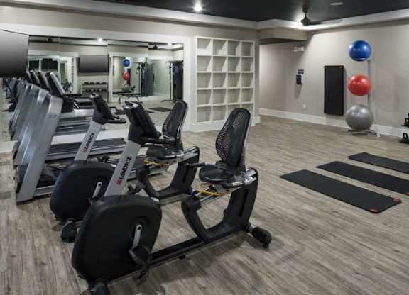 a gym with a row of exercise bikes and a large mirror