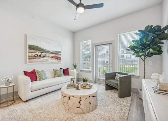A living room with a white couch, a coffee table, and a painting on the wall.