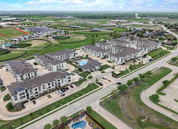 A bird's eye view of a residential area with multiple houses and a swimming pool.