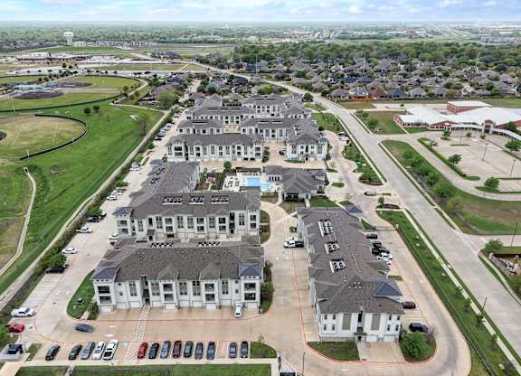 A large, modern residential complex with multiple buildings and a parking lot.
