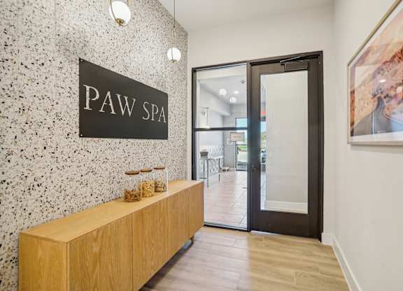 a lobby with a pay spa sign on the wall and a wooden reception desk