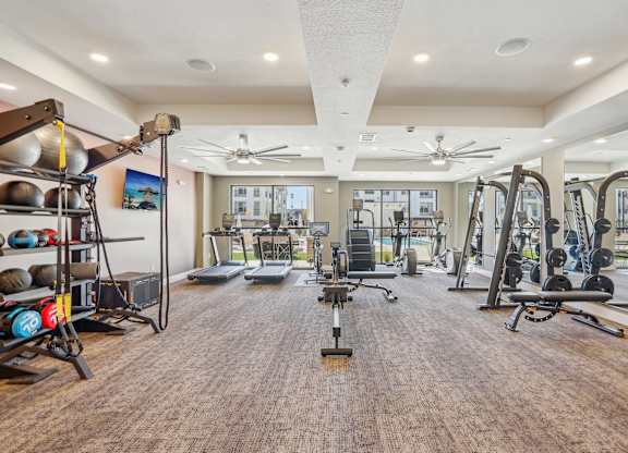 a gym with weights and cardio equipment in a building with windows