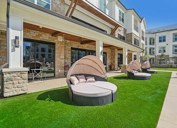 a patio with round chairs and a lawn in front of a building