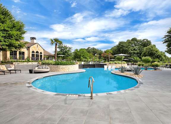 Resort-style pool with curved edge, stone landscaping, and wide sun deck seating.
