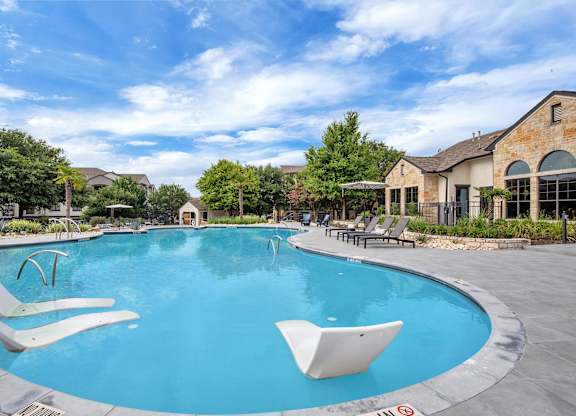 Wide view of the freeform pool with in-water loungers and surrounding sun deck.