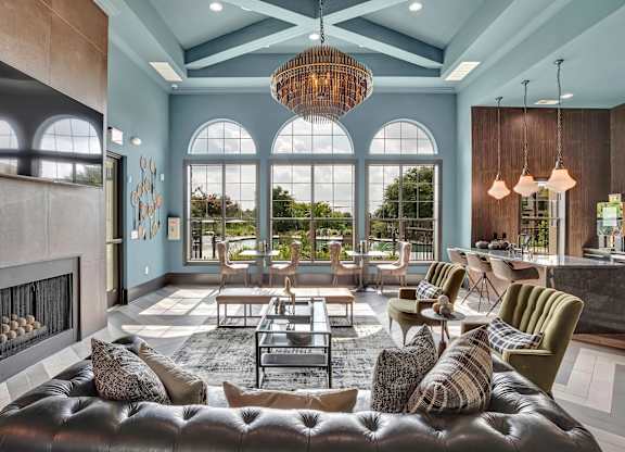 Resident lounge with arched windows, chandelier lighting, and seating near a bar.