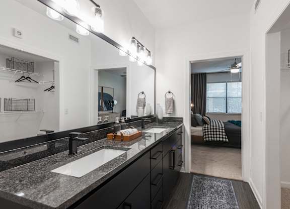 Bathroom with double-sink vanity, granite countertop, and walk-in closet access.