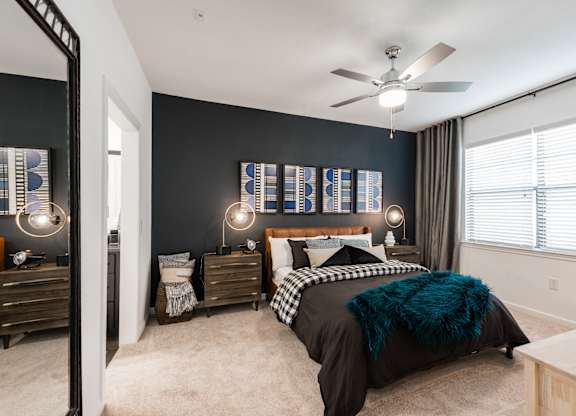 Bedroom view with nightstands, modern lighting, and soft carpet under a ceiling fan.
