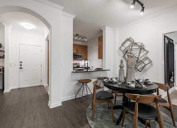 Dining nook with arched entryway and kitchen bar seating in an open floor plan.