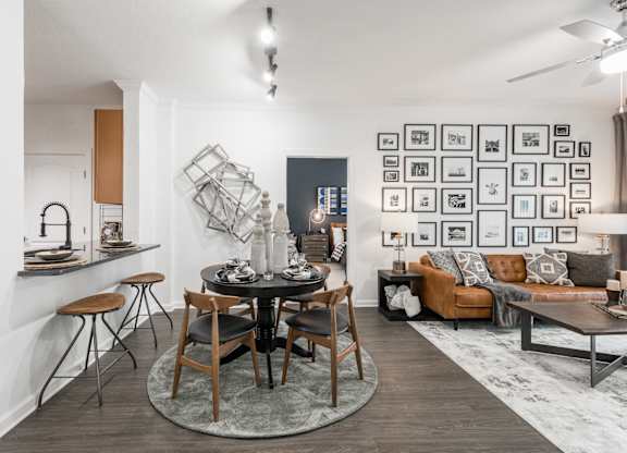 Round dining table set beside a pass-through counter, with living room seating nearby.
