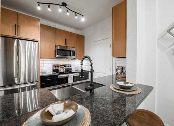Kitchen island with granite countertop, undermount sink, and stainless steel appliances.