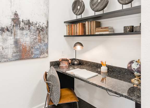 Built-in desk nook with granite work surface, floating shelves, and task lighting.