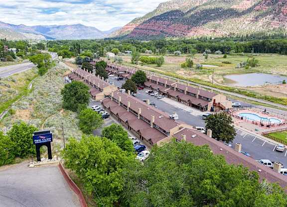 an aerial view of a building with a parking lot and mountains in the background