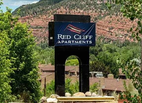 a sign that says red cliff apartments with a mountain in the background