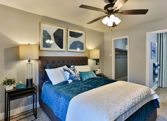 A bedroom with a bed, two lamps, and a ceiling fan.