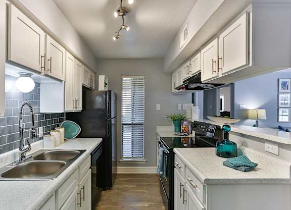 A kitchen with black appliances and white cabinets.