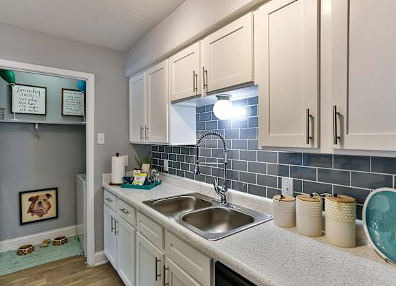 A kitchen with white cabinets and a blue tile backsplash.
