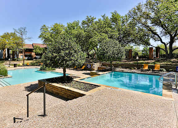 A pool surrounded by trees and a gravel area.