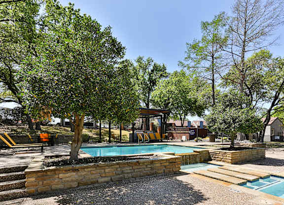 A pool surrounded by trees and a stone wall.