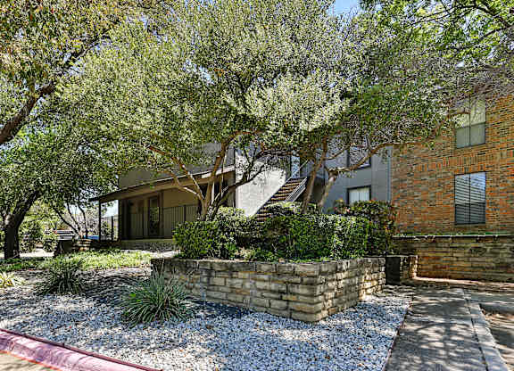 A house with a stone wall and a tree in front.