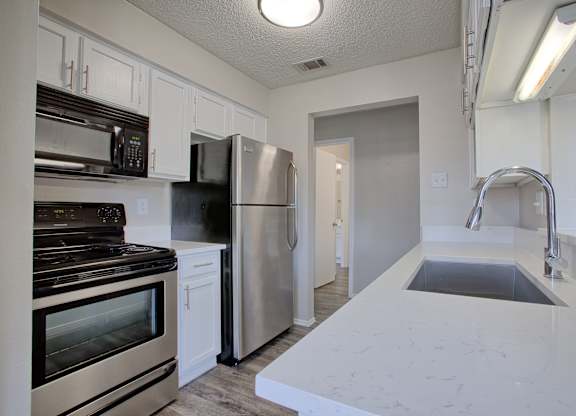 A kitchen with stainless steel appliances and white cabinets.