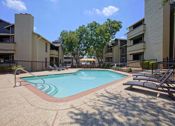 A swimming pool surrounded by apartment buildings on a sunny day.