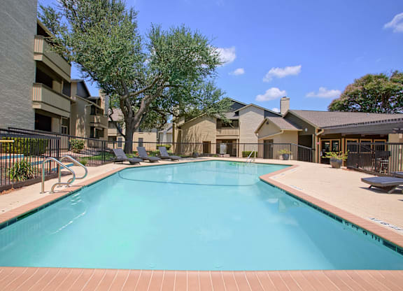 A large swimming pool surrounded by a fence and buildings.