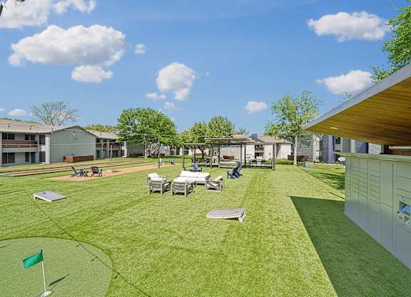 a backyard with tables and chairs on a grass field