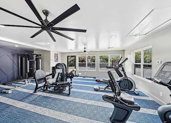 a gym with exercise machines and a ceiling fan