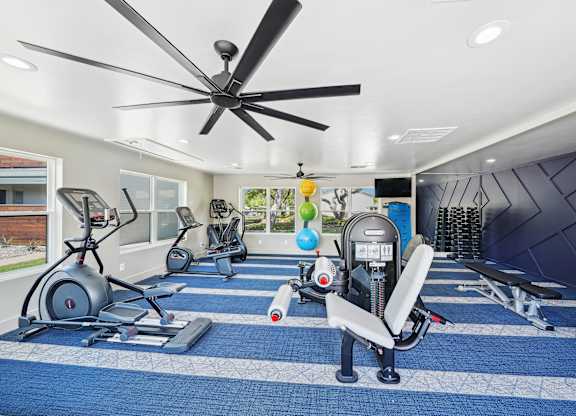 a home gym with exercise equipment and a ceiling fan