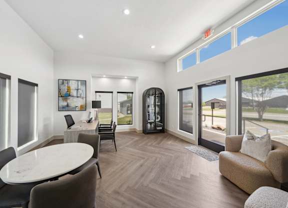 a living room with couches and a round table and windows
