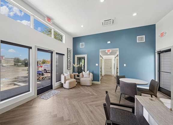 a living room with blue walls and a large window and a table and chairs