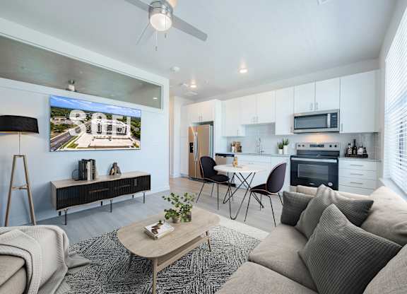A modern living room with a grey couch, a wooden coffee table, and a flat screen TV mounted on the wall.