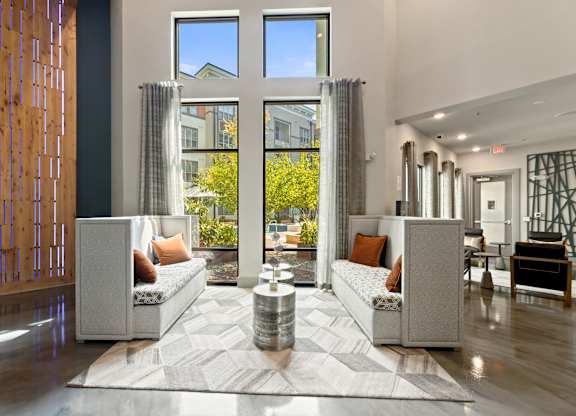 A modern living room with a large window and a wooden partition on the left.