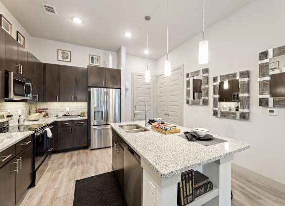 A modern kitchen with dark brown cabinets and stainless steel appliances.