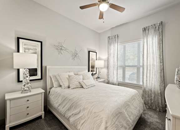 A bedroom with a bed, nightstand, and a ceiling fan.