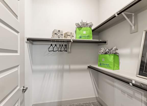 A white closet with two shelves and two green boxes on top.