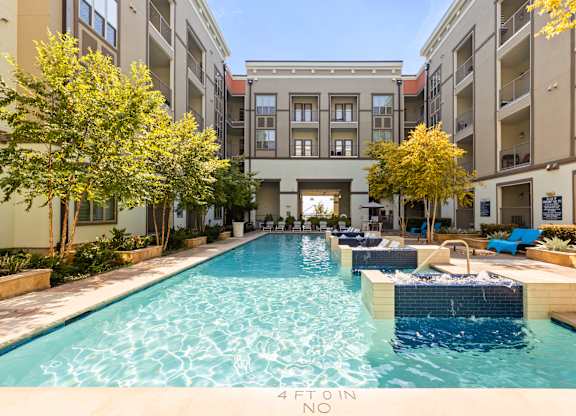 A swimming pool in a courtyard surrounded by trees and buildings.