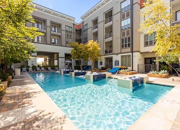 A large swimming pool in front of apartment buildings.