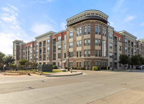 A large, multi-story building with a flat roof and a parking lot in front.