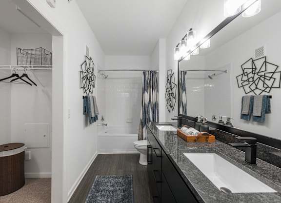 Full bathroom with double vanity, framed mirror, and tub-shower combination.