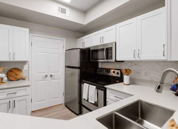 Updated kitchen with white shaker cabinets, stainless steel appliances, and quartz-style countertops.
