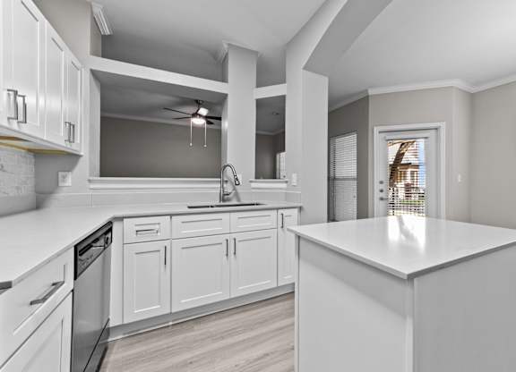 White kitchen island with surrounding cabinetry, breakfast bar, and nearby patio door.