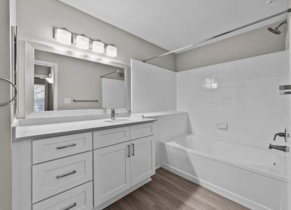 Bathroom with white vanity, integrated sink, and tub-shower combination with tile surround.