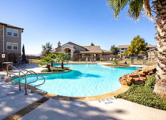 Bright poolscape with island planters, lounge chairs, and clubhouse backdrop.